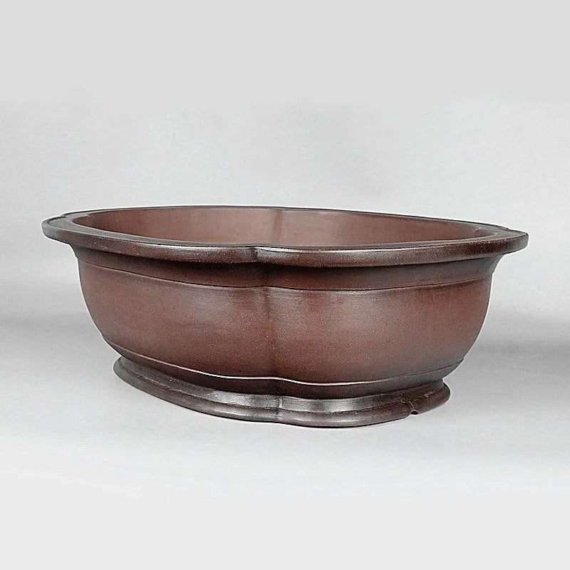 Handmade antique crabapple shaped purple clay flowerpot on a wooden floor.