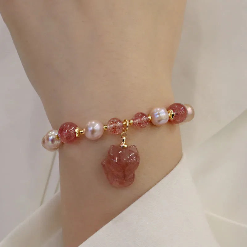 Women's light pink freshwater pearl bracelet with a small fox charm on a natural background.