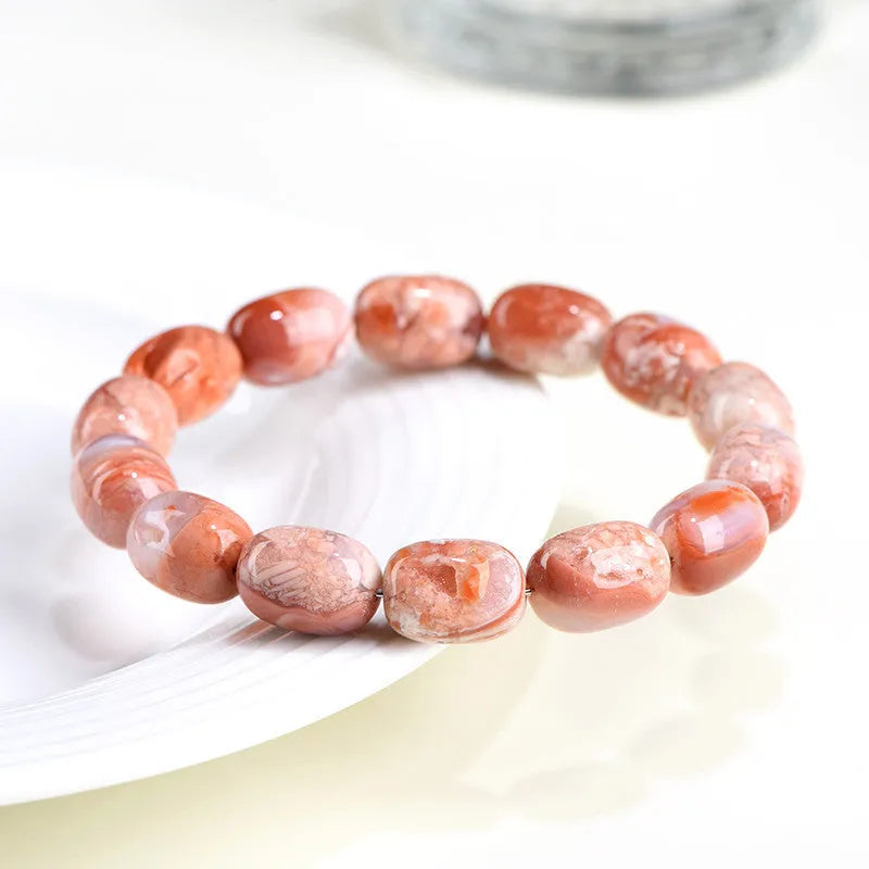 Natural cherry agate bracelet with barrel-shaped beads and a gold Ruyi charm on an adjustable strap.