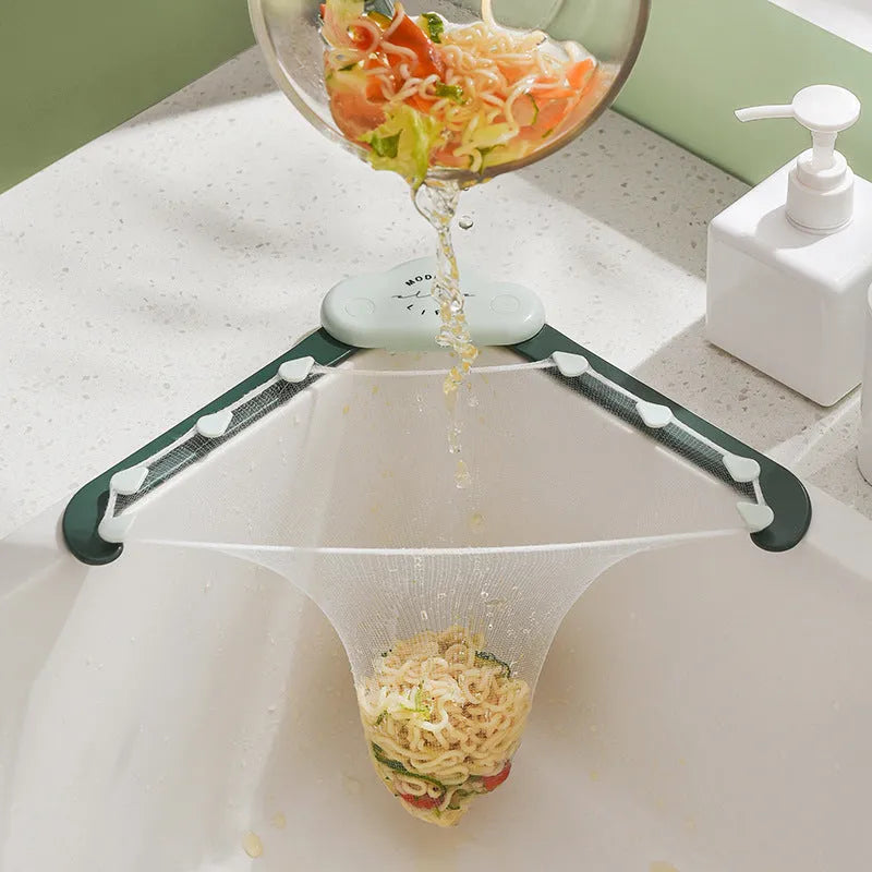 Triangular grey sink drain rack with filter mesh bag installed on a kitchen countertop.