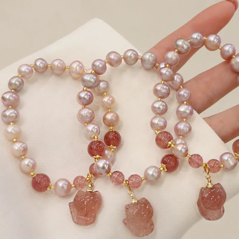 Women's light pink freshwater pearl bracelet with a small fox charm on a natural background.