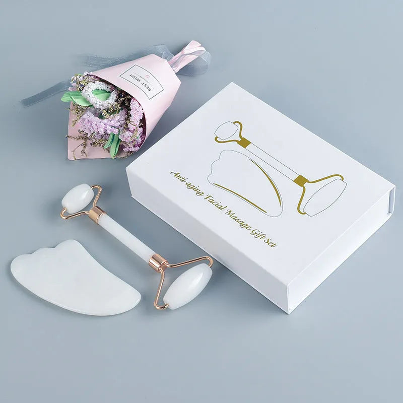 White jade facial roller set with double-headed roller claw and scraping board on wooden surface