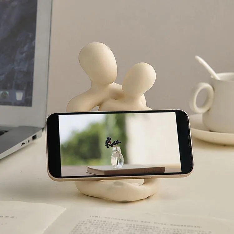 Modern minimalist loving couple resin statue in milky white on a wooden desk.
