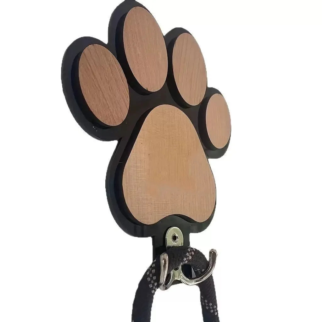 Black wooden wall hook with raised paw print design against a white wall.