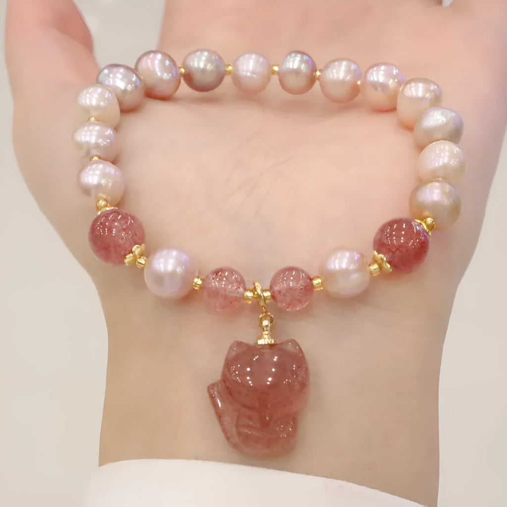 Women's light pink freshwater pearl bracelet with a small fox charm on a natural background.