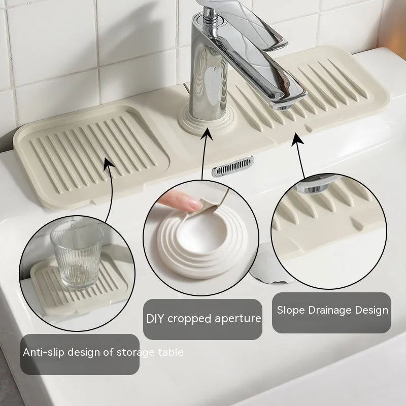Beige silicone sink splash guard with sloped design and drainage channels placed under a kitchen faucet.
