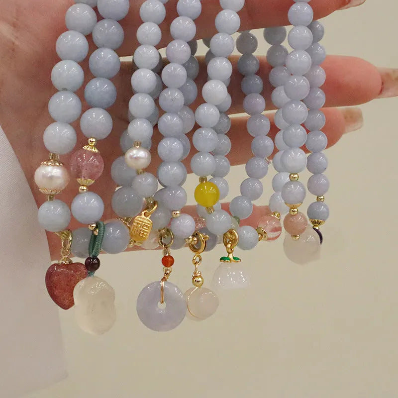 Gold plated bracelet with a detailed artificial crystal charm pendant on a woman's wrist.