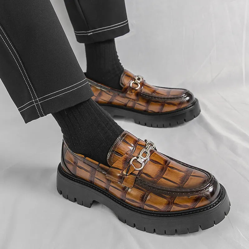 Men's black crocodile pattern loafers with a flat platform sole on a plain background.