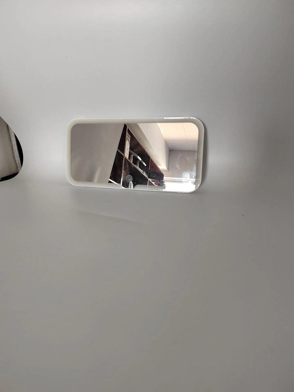 White car sun visor with rectangular LED-lit make-up mirror mounted on it.