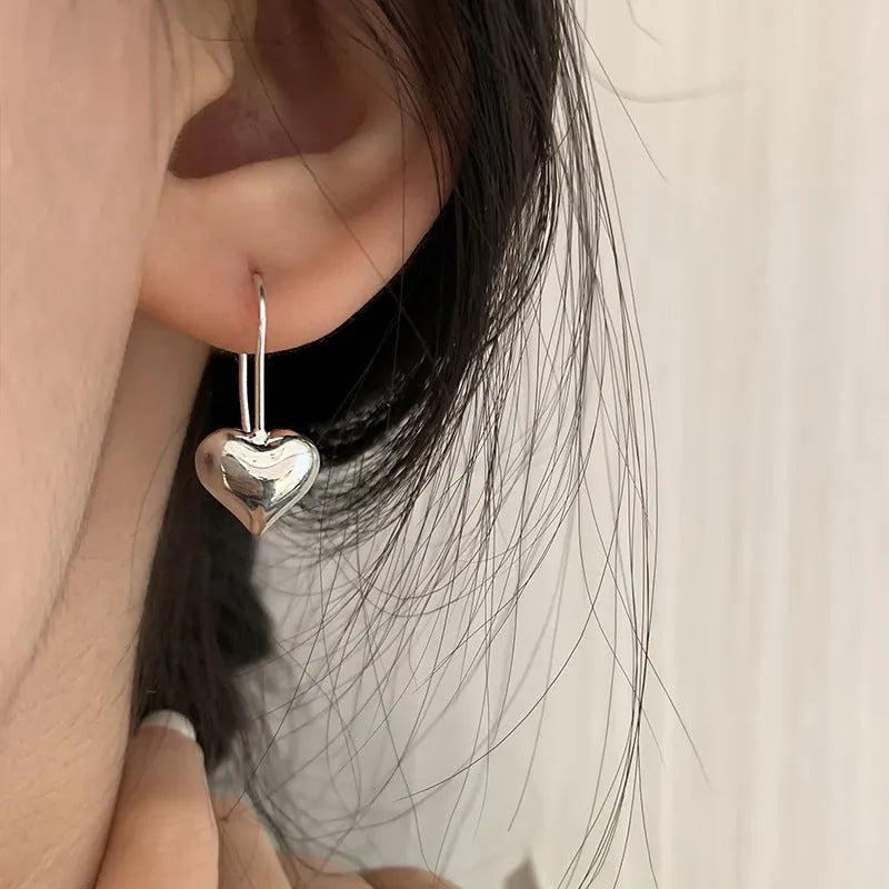 Silver coloured heart-shaped earrings with three-dimensional glossy finish and Korean style design