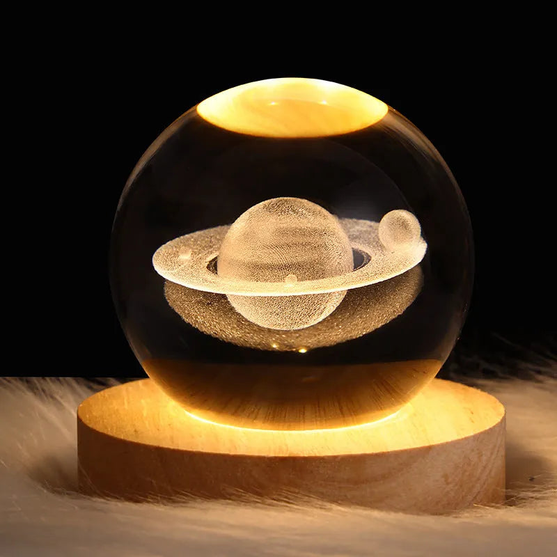 LED galaxy crystal ball night light with 3D planet designs on a table