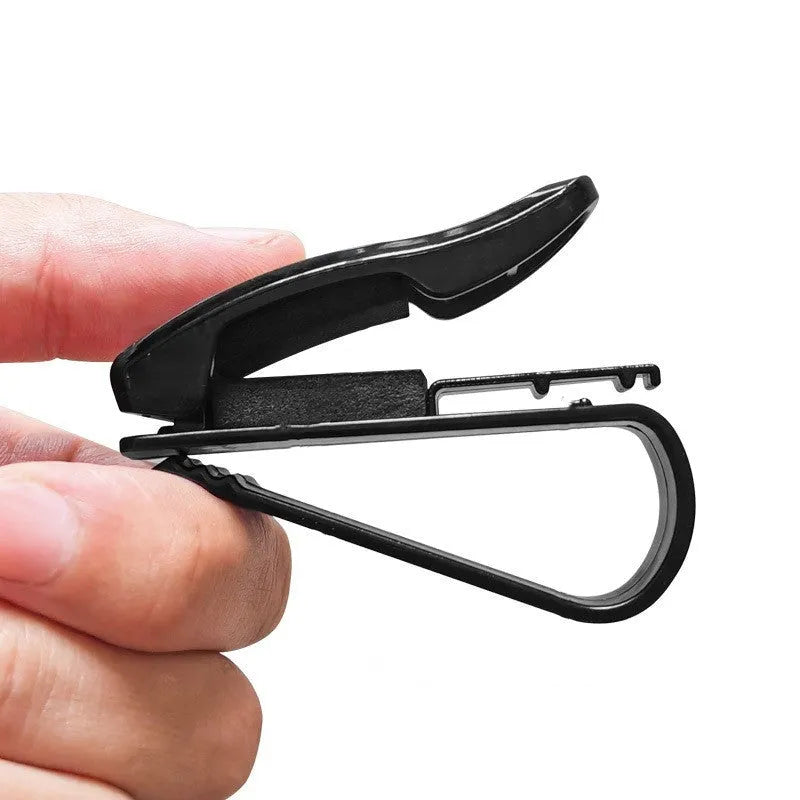 Black plastic multifunctional clip for car sunshades, holding sunglasses and a card.