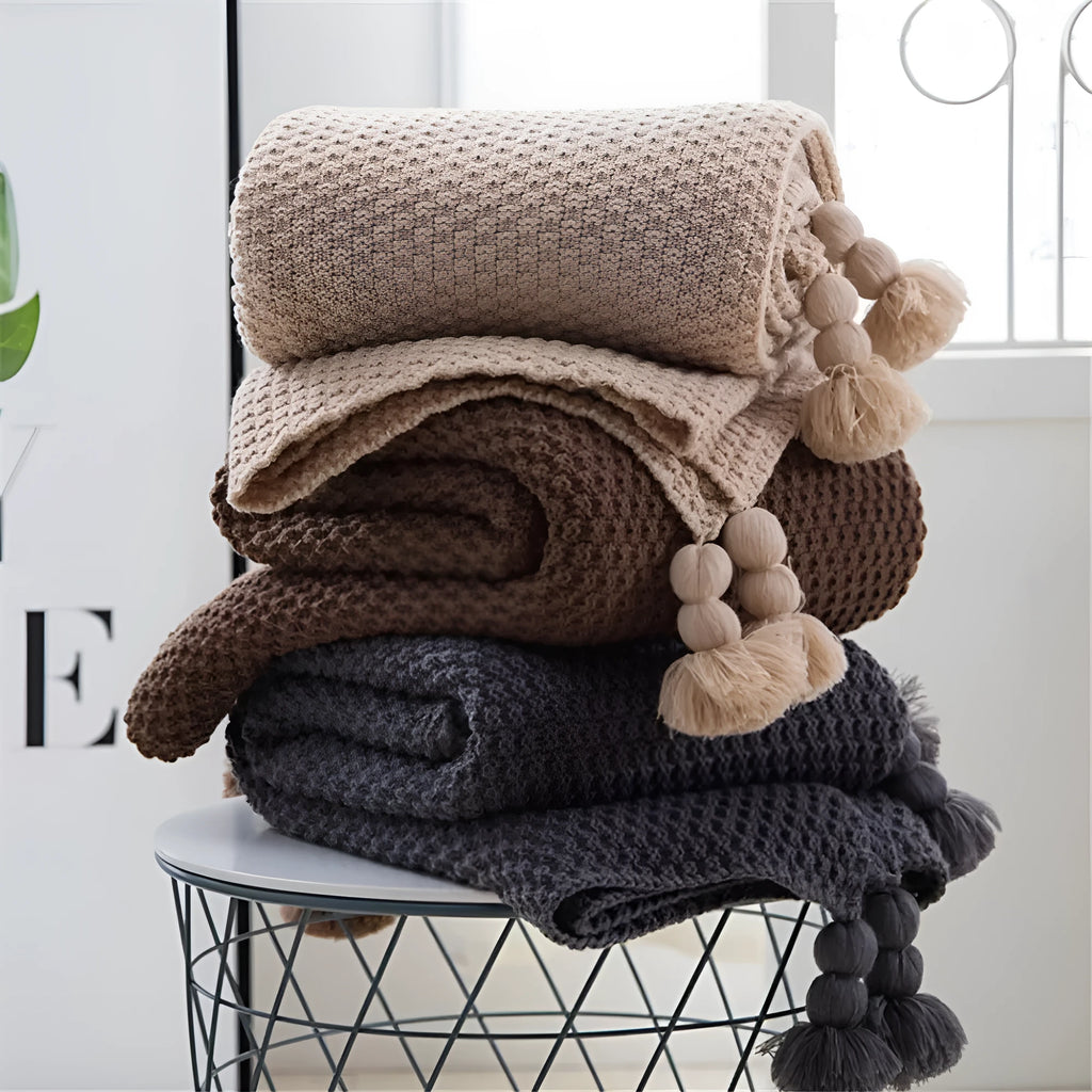 Nordic fringed knit ball acrylic blanket in beige colour, measuring 130 by 170 centimetres.