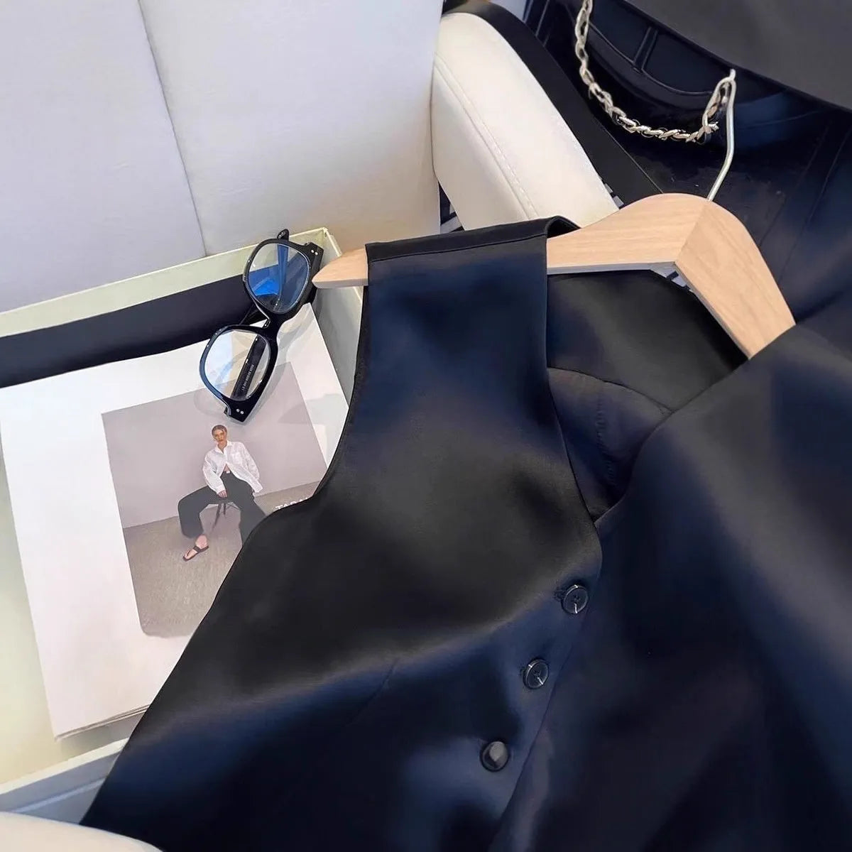 Black satin ladies' sleeveless vest on a hanger, showing loose fit.