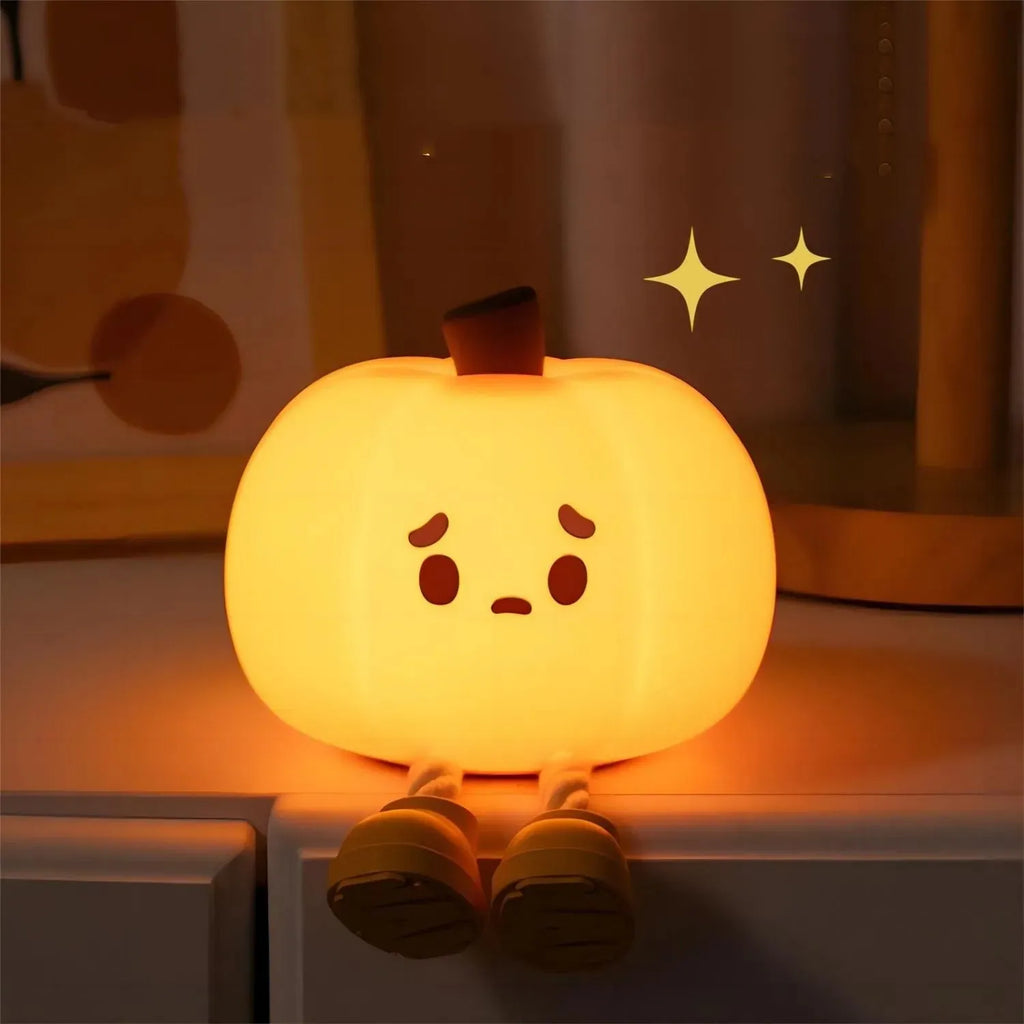 Soft orange silicone pumpkin-shaped night light with a warm glowing face on a table.