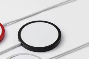 Silver metal Magsafe wireless charger for Apple iPhone on a table.