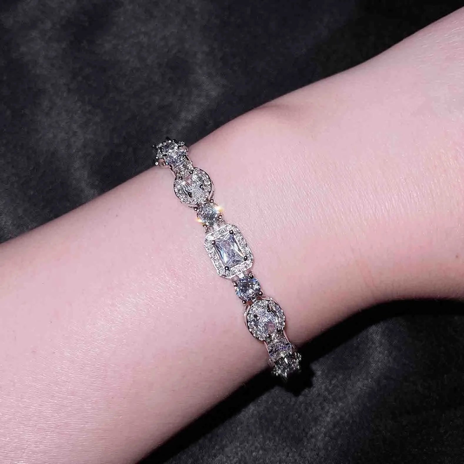 Women's geometric silver bracelet with zircon stones on a white background.