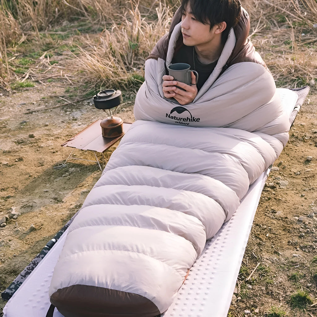Goose down mummy sleeping bag in a stuff sack, part of the snowbird range for camping.