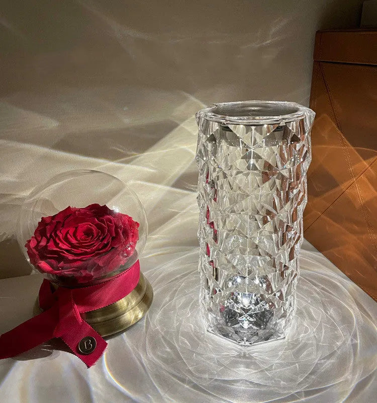 Creative acrylic crystal rose LED table lamp with adjustable three-colour lighting on a wooden surface.