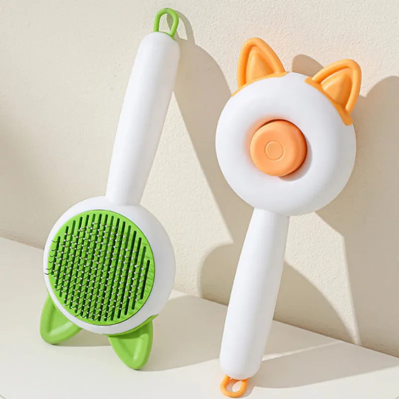 Greenish white cat grooming brush with stainless steel teeth and a self-cleaning button on the handle.