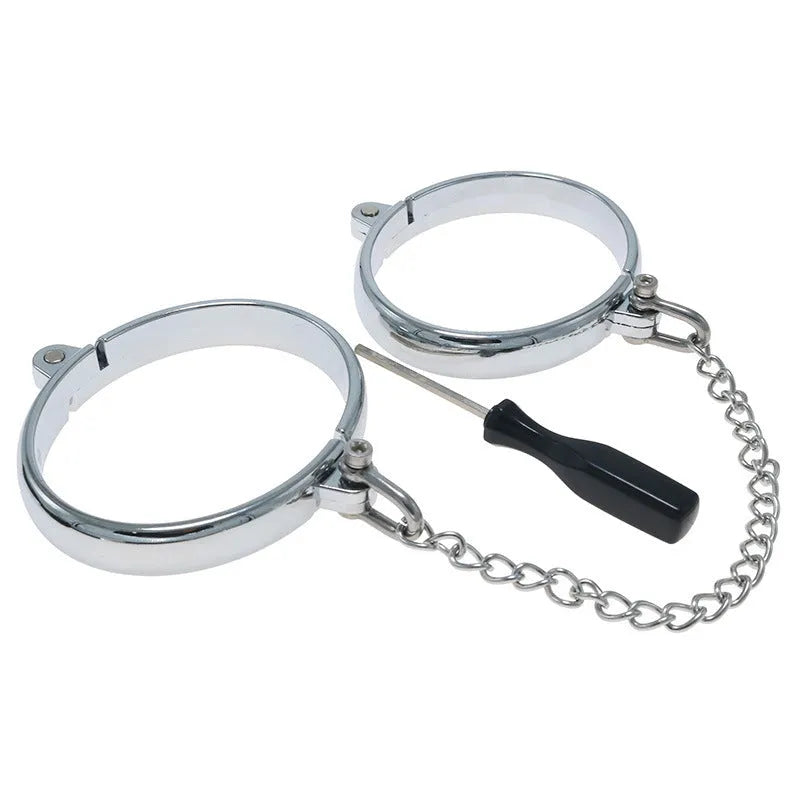 Silver zinc alloy metal handcuffs and footcuffs set for adult bondage play on a dark background.