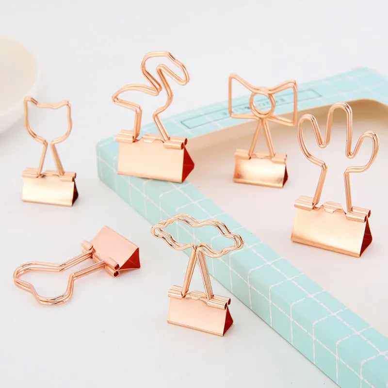 Small gold metal office clip with long tail, showing flamingo, love, cloud, cat, cactus, and bow shape options.