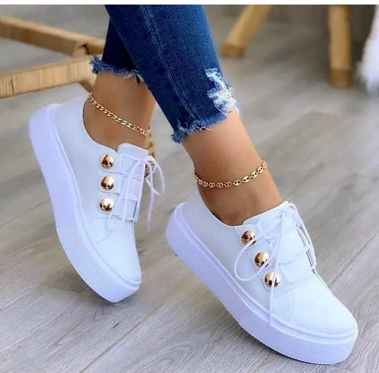 Women's white lace-up flats sneakers with decorative silver rivets on the artificial PU upper.