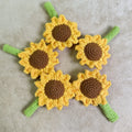 Hand-woven rattan sunflower pen cover holding a wooden pen on a desk.