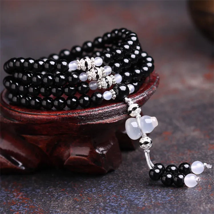 Black agate bracelet with 108 geometric beads and number details on a wrist.
