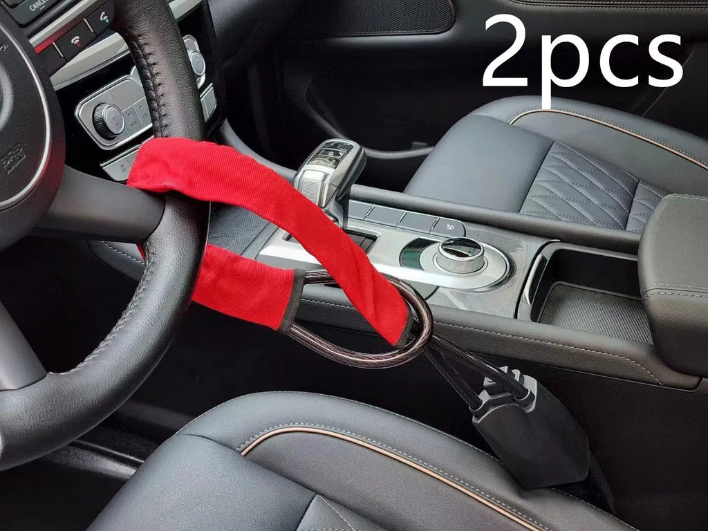 Red car steering wheel lock with iron cable secured around a steering wheel.