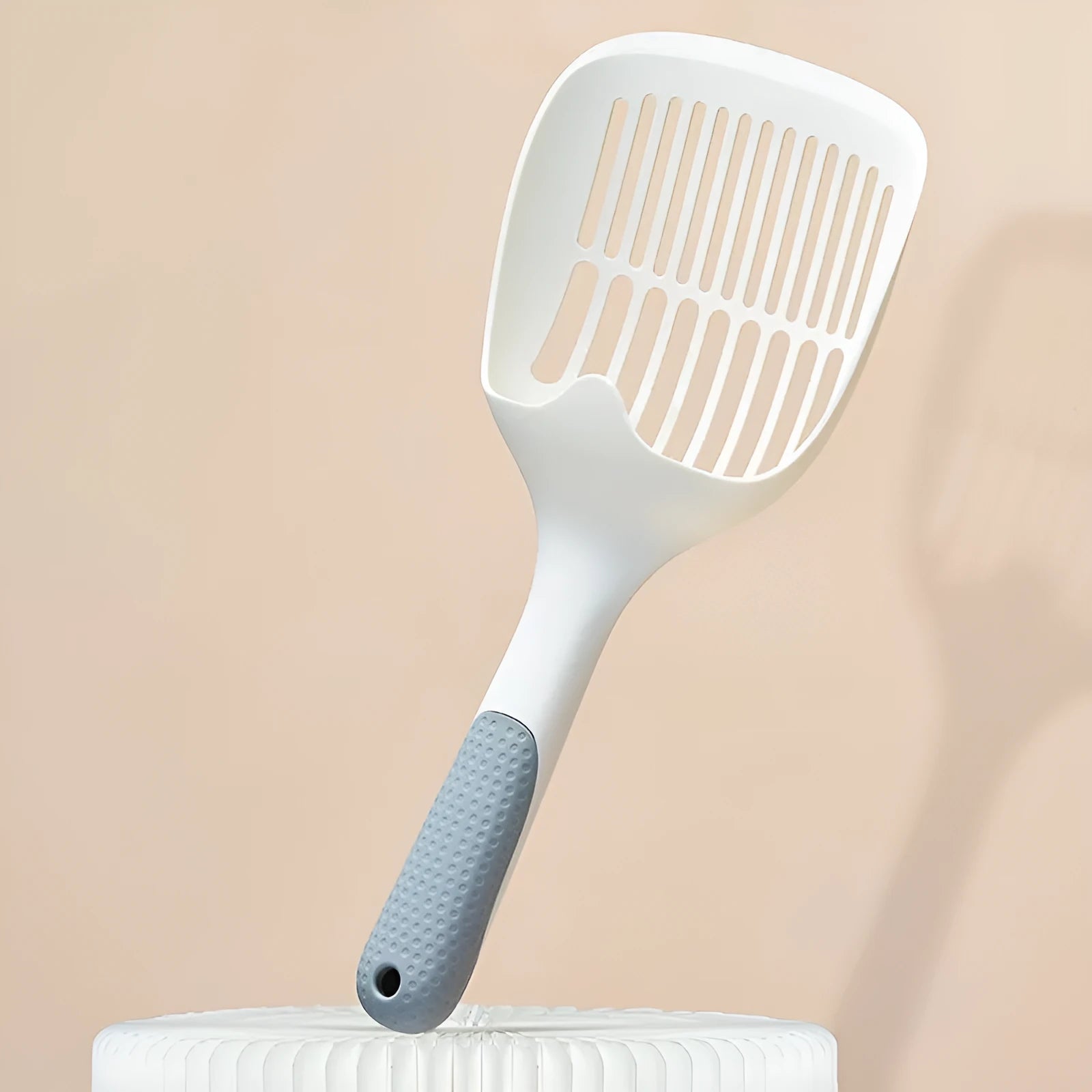 White plastic cat litter scoop with attached storage base on a white background.