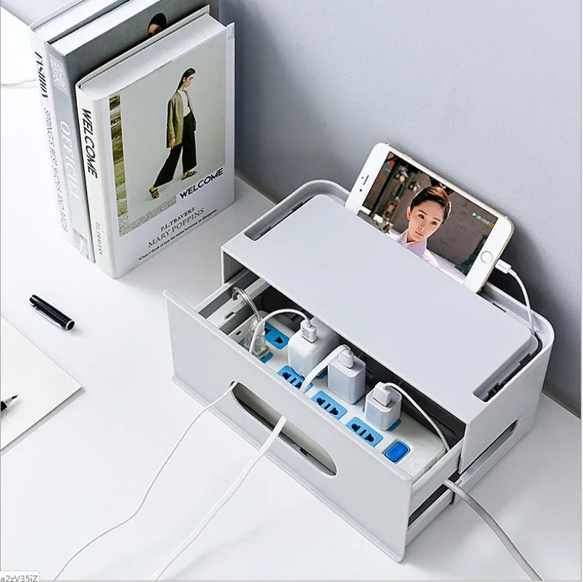 White plastic wireless router storage box with cable slots on a desk next to a router.