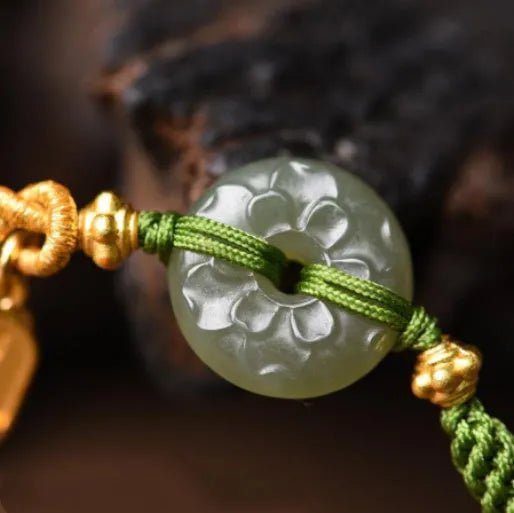 Close-up of a women's hand-woven green rope bracelet with a Hetian jade peace buckle charm.