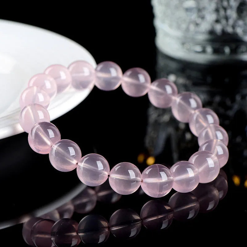 Women's pink polished crystal round bead bracelet in natural starlight style on a white background.