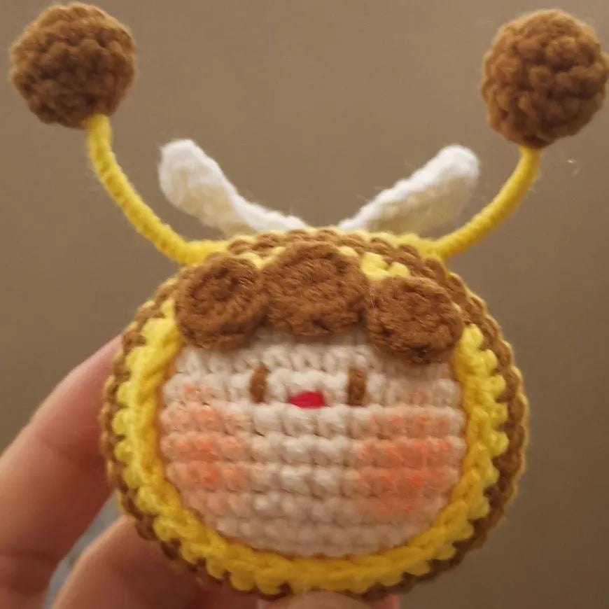 Handmade crocheted plush bee hive and bees accessory for woolen dolls on a white background.