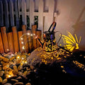 Solar-powered iron garden lamp with a tapered butterfly design emitting warm white LED light.