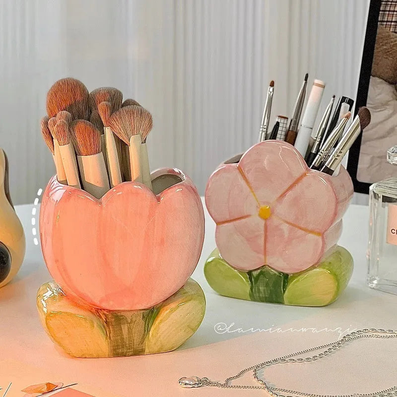 Ceramic pen holder box with floral decoration on a desk, holding pens.