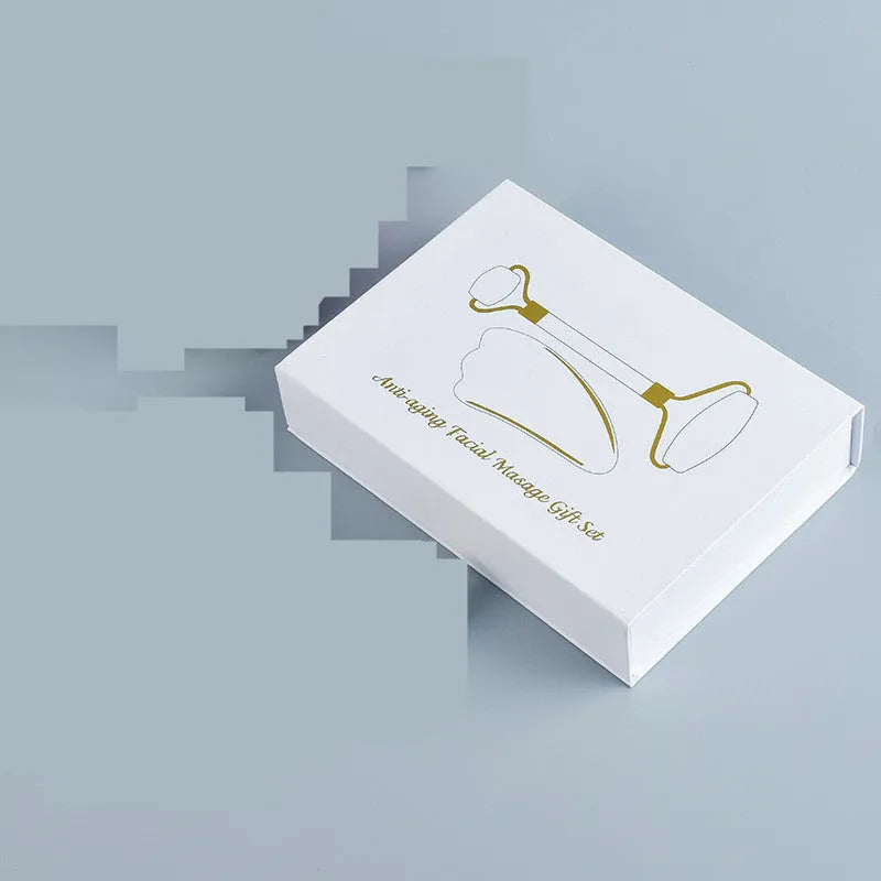 White jade facial roller set with double-headed roller claw and scraping board on wooden surface