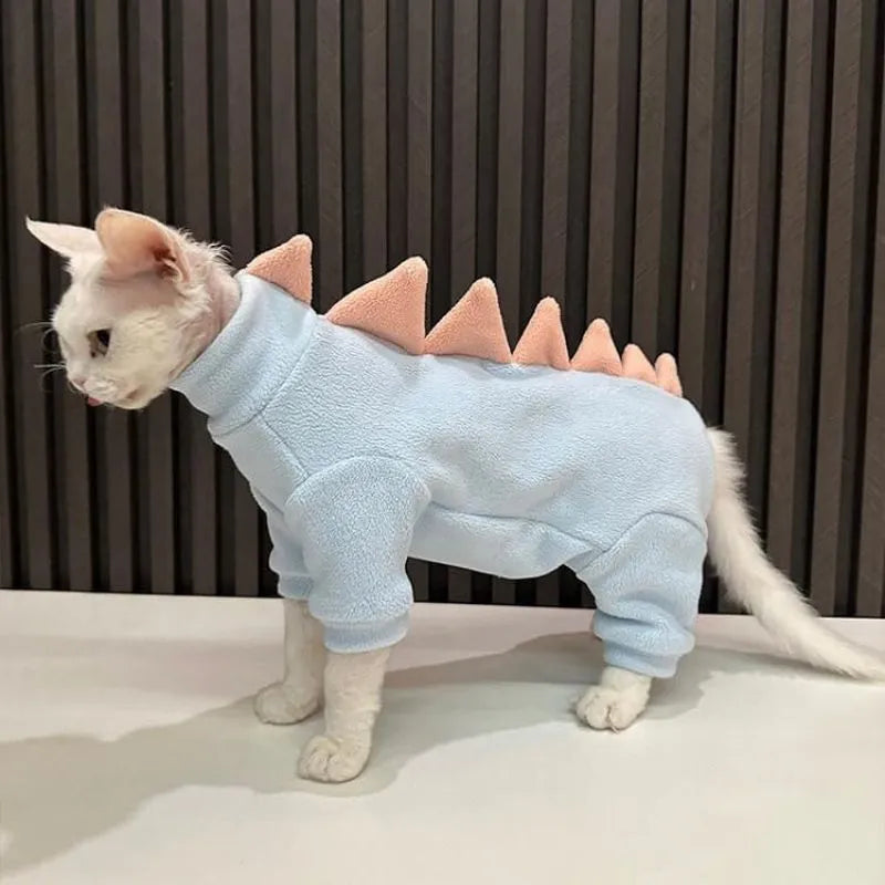 Sphynx cat wearing a green fleece dinosaur costume with a tail and spine spikes