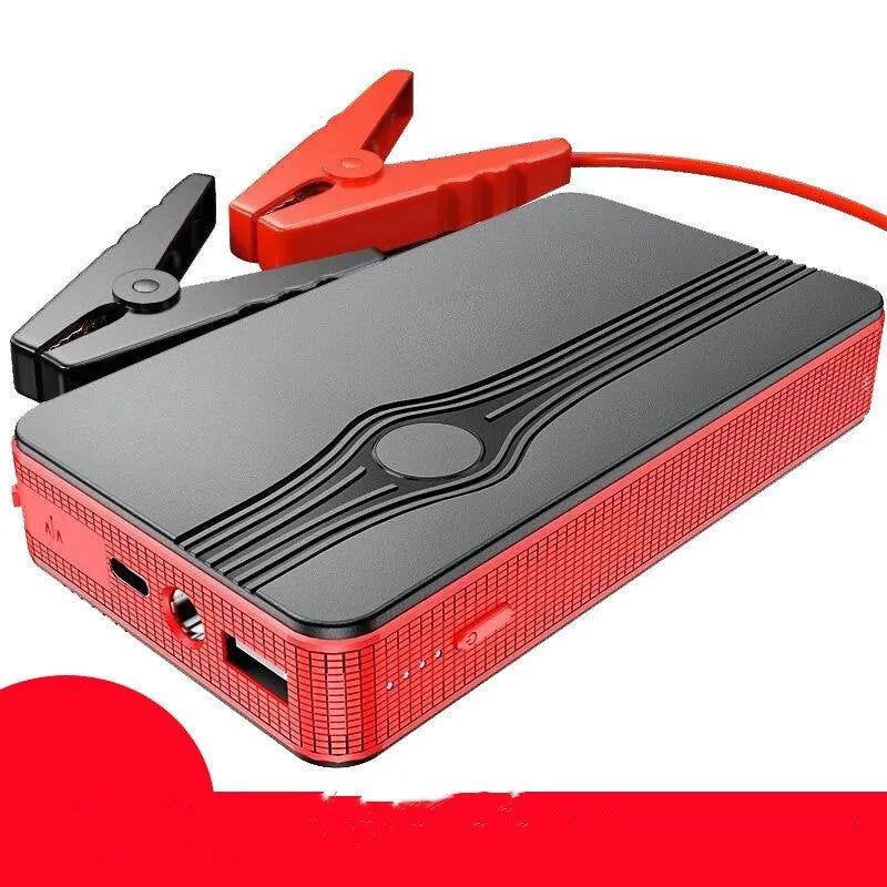 Red K4-E automobile emergency jump starter power supply unit with a USB cable on a table.