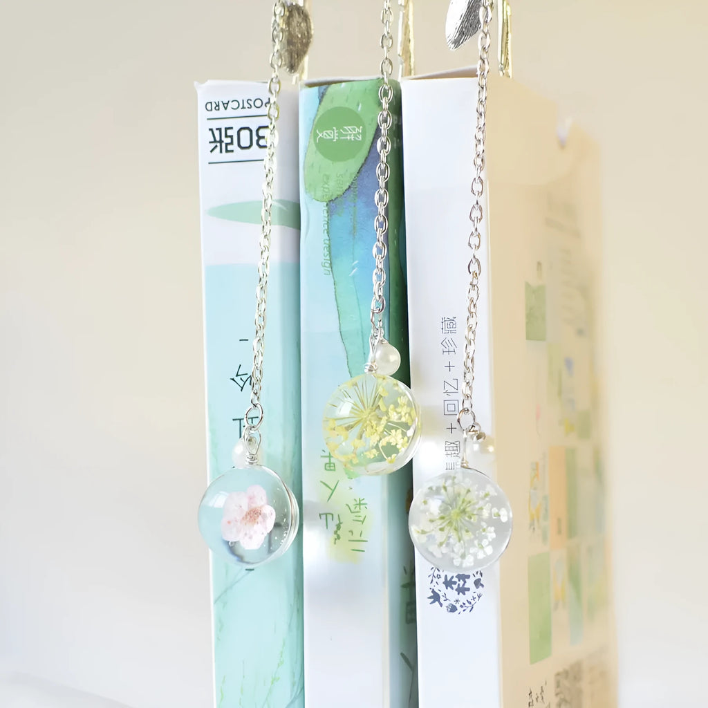 Flat metal bookmark with a dried flower inside, showing colour options like blue starry sky and dandelion.