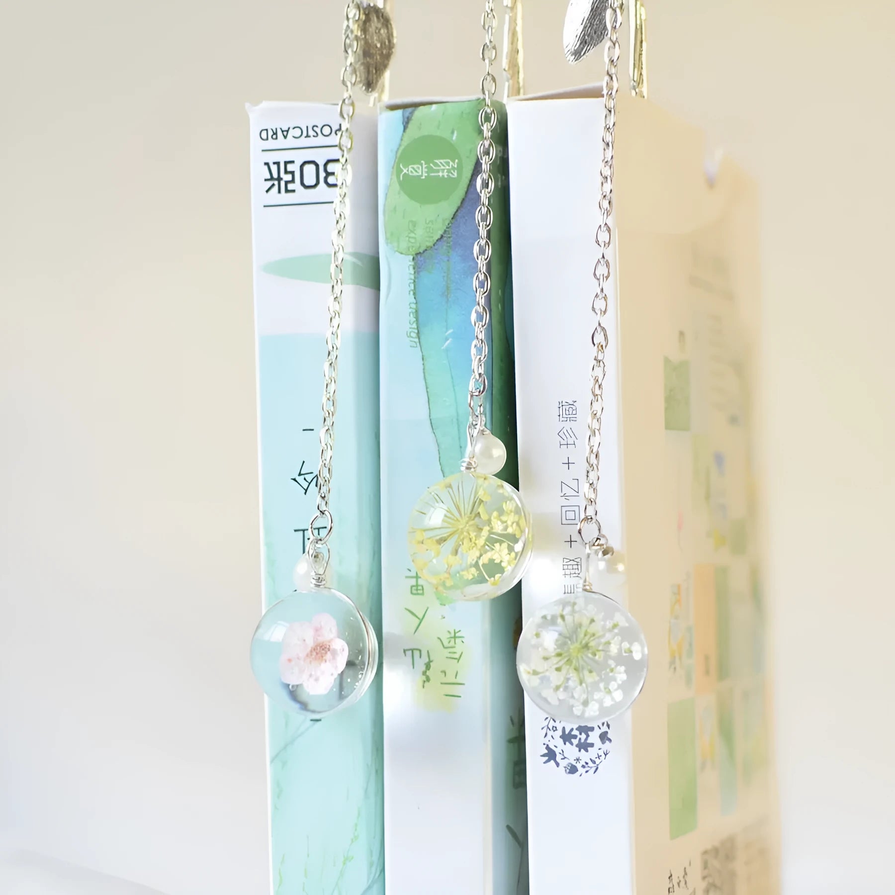 Flat metal bookmark with a dried flower inside, showing colour options like blue starry sky and dandelion.