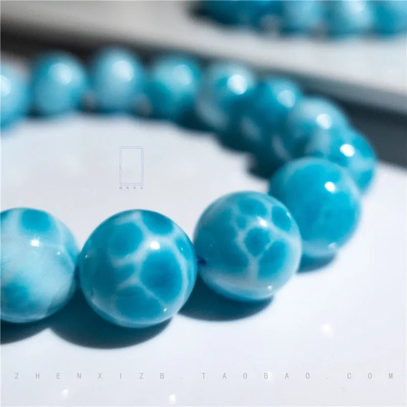 Blue Bodhi bead bracelet with white pearl accents on a plain background.