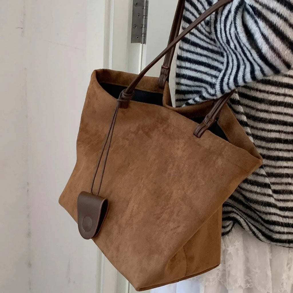 Brown suede shoulder bag with double straps and sewing line detail on a white background