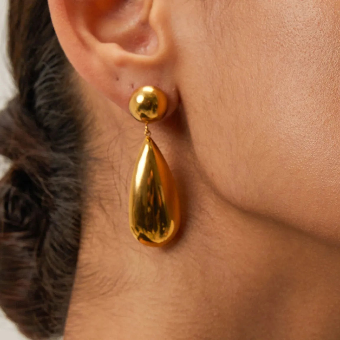A pair of gold-coloured stainless steel earrings with a geometric water drop and hemisphere pendant design.