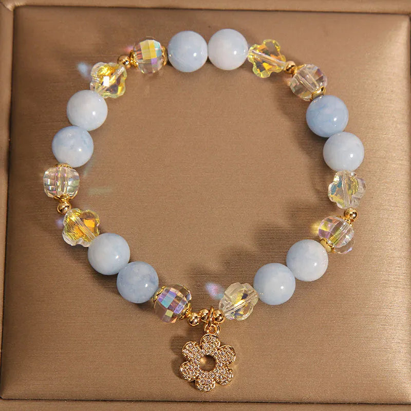 Women's aquamarine crystal bracelet with a four-leaf clover charm and pearl detail.