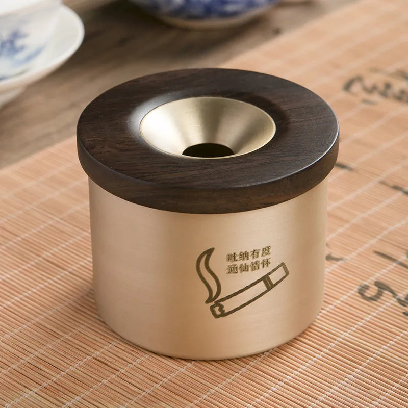 Brass-coloured copper ashtray with a wooden lid on a tabletop.