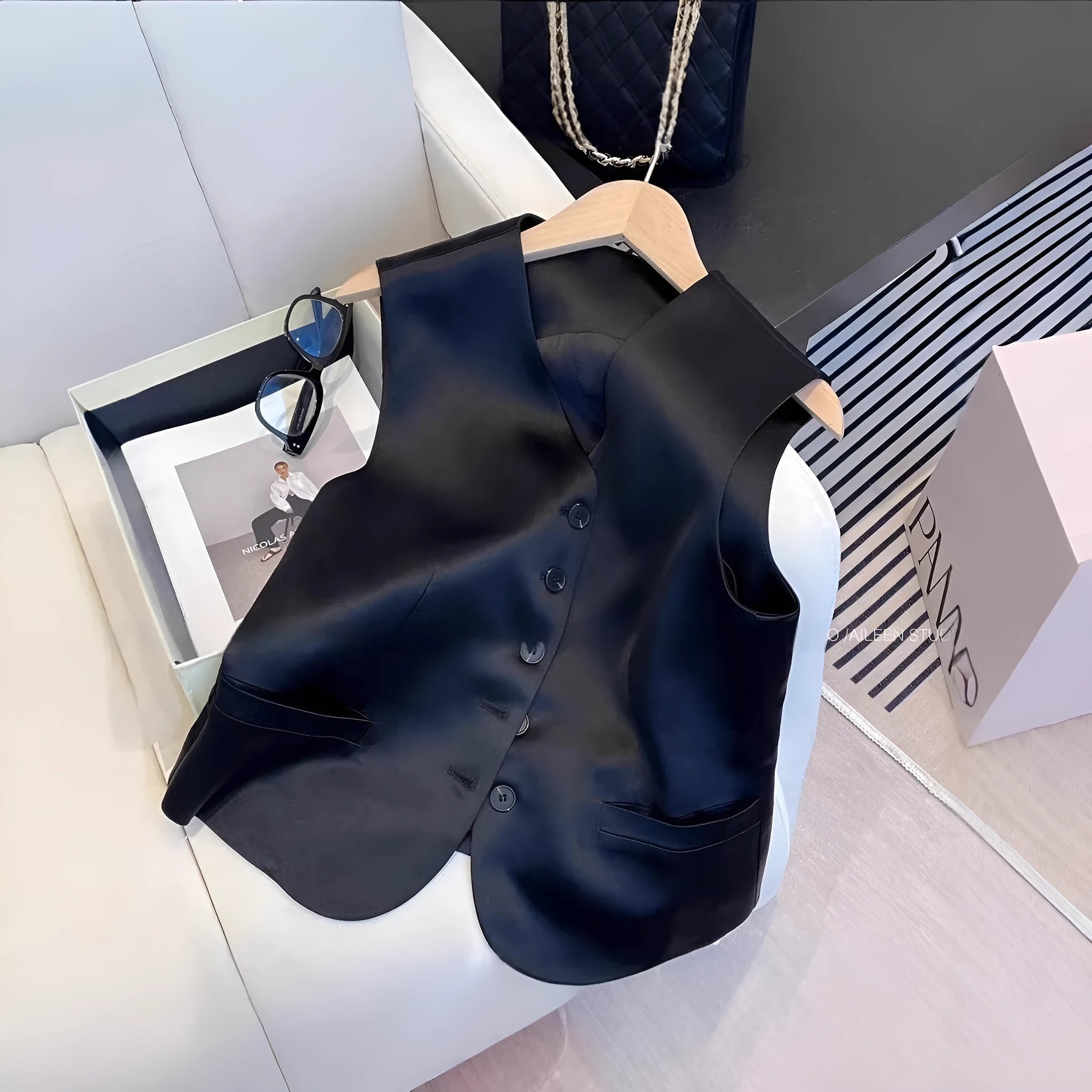 Black satin ladies' sleeveless vest on a hanger, showing loose fit.