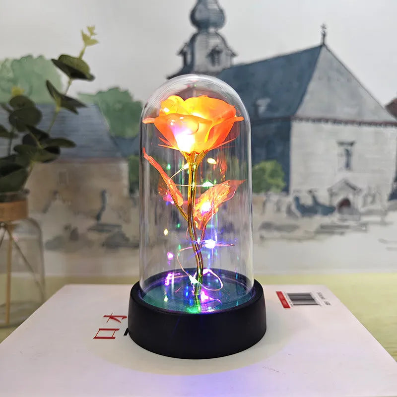 Small glass dome night lamp with colourful plastic flowers inside on a black base.
