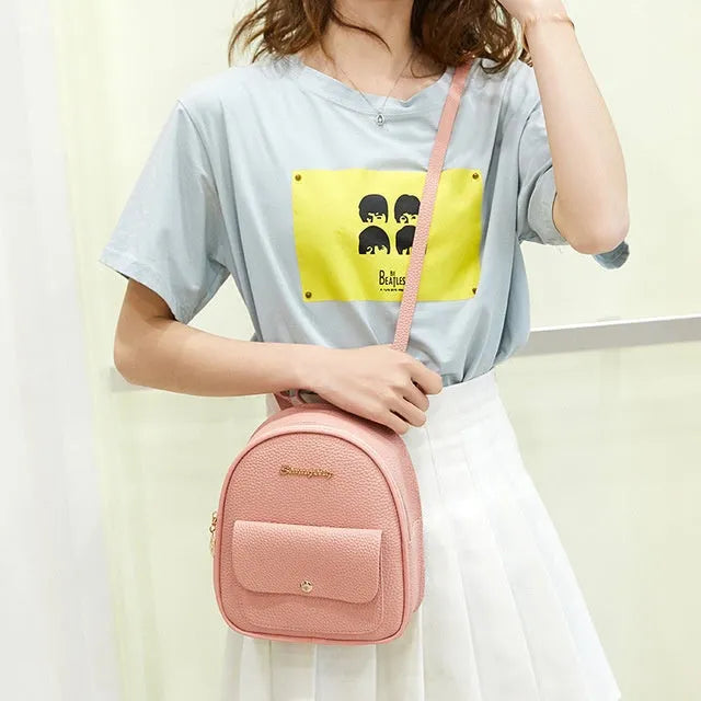 Black PU women's small backpack convertible to a shoulder bag, shown with a mobile phone for scale.